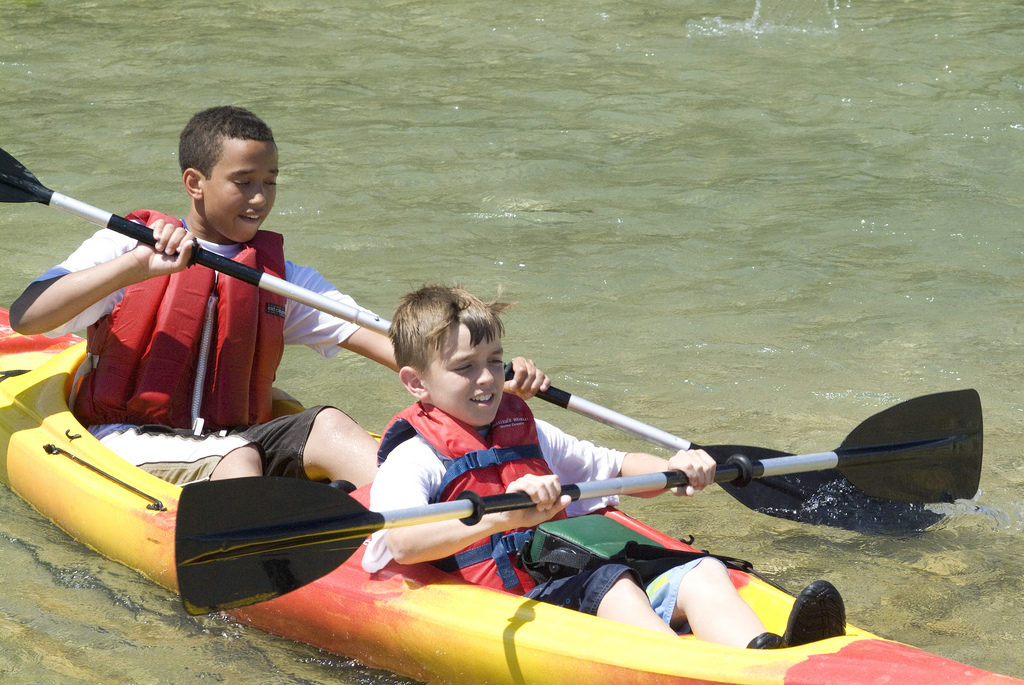 children kayaking water activities at summer camp