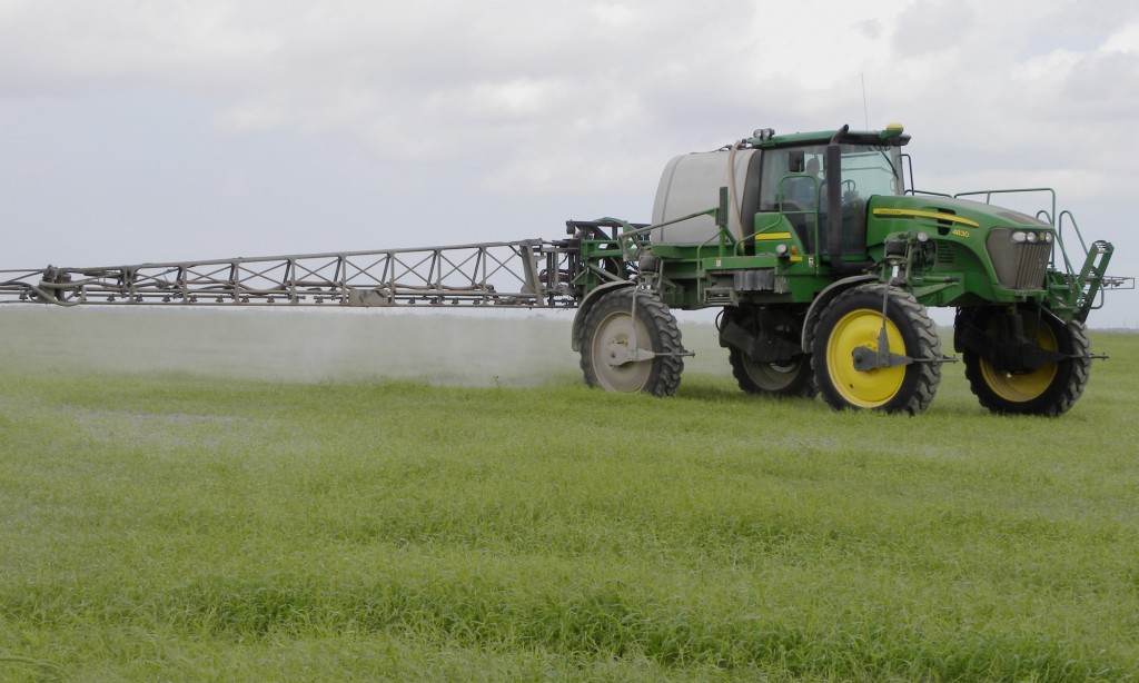 un tractor verde con una plataforma de pulverización adjunta aplica pesticidas