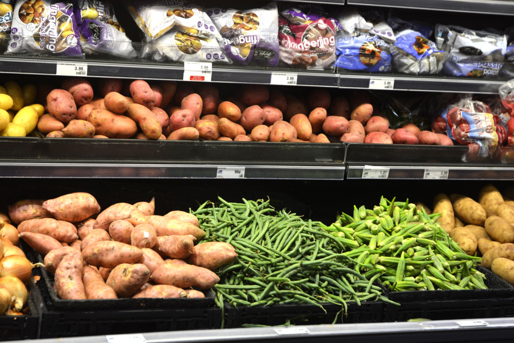 Grocery shelves full of food such as potatoes, beans and other produce