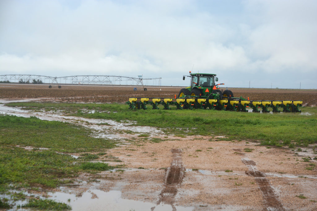 Harvester moving through flooded portion of field 