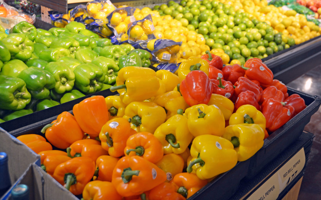 Orange, yellow, red and green bell peppers on display at a grocery store