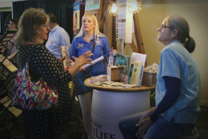 Deborah Sauer-Bullis and Jane Duke with AgriLife Extension talk to a visitor at AgriLife Extension's booth display at the State Fair of Texas