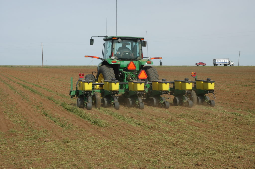 A green tractor pulling seeding boxes - pre-plant planning is important