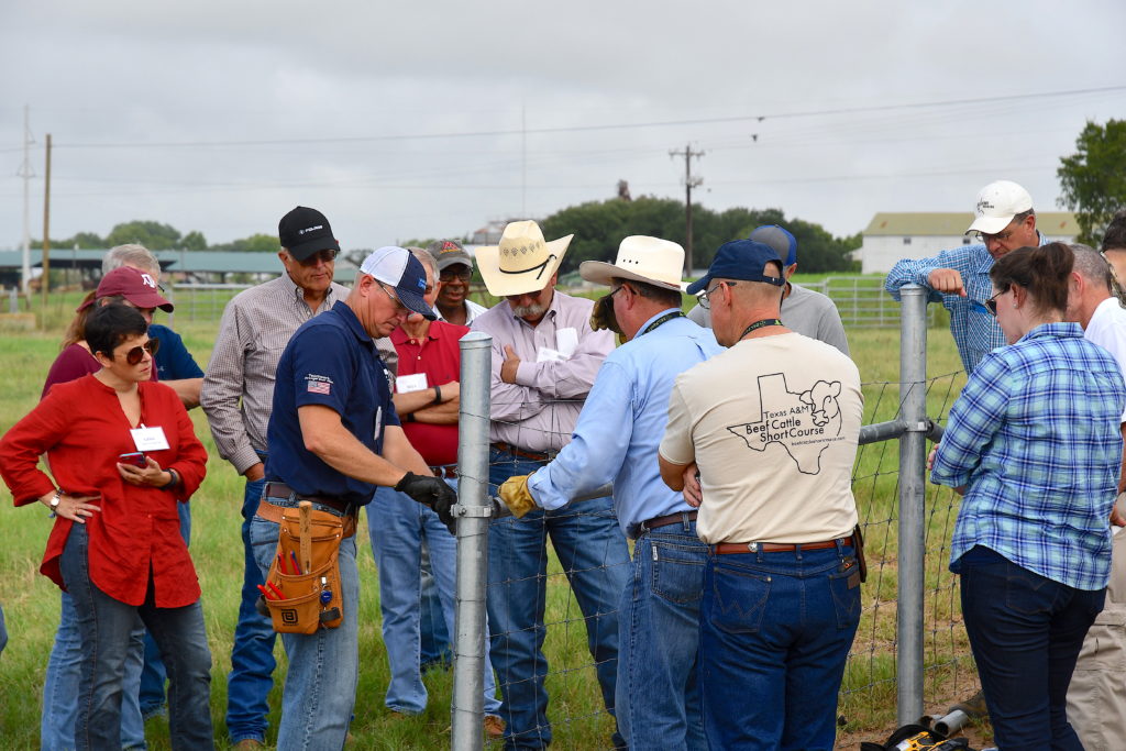 People stand around looking at a man during fence-building demonstrations.