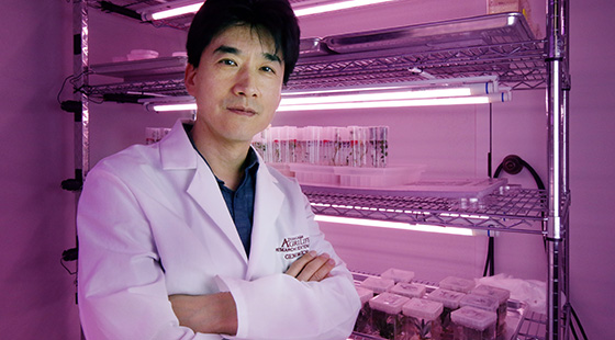 Man, Junqi Song, standing cross-armed in lab