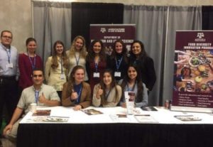 A group of students posing around a booth table