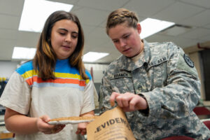 Two female students placing a footprint cast into an evidence envelope