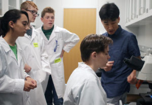 Scientists coaches students on microscope