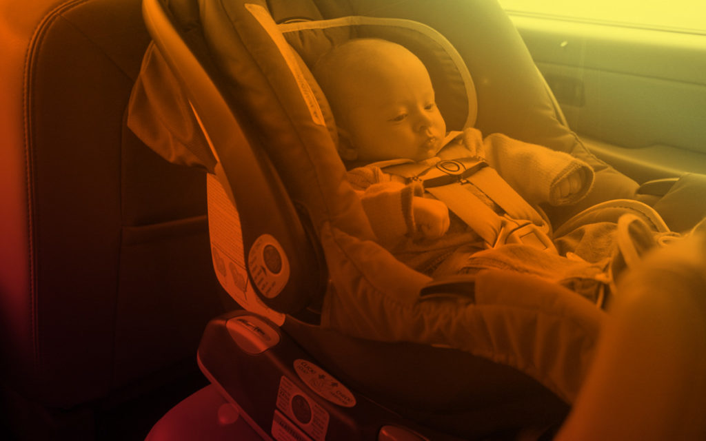 Child in safety seat in back of vehicle with filter coloring to represent heat.