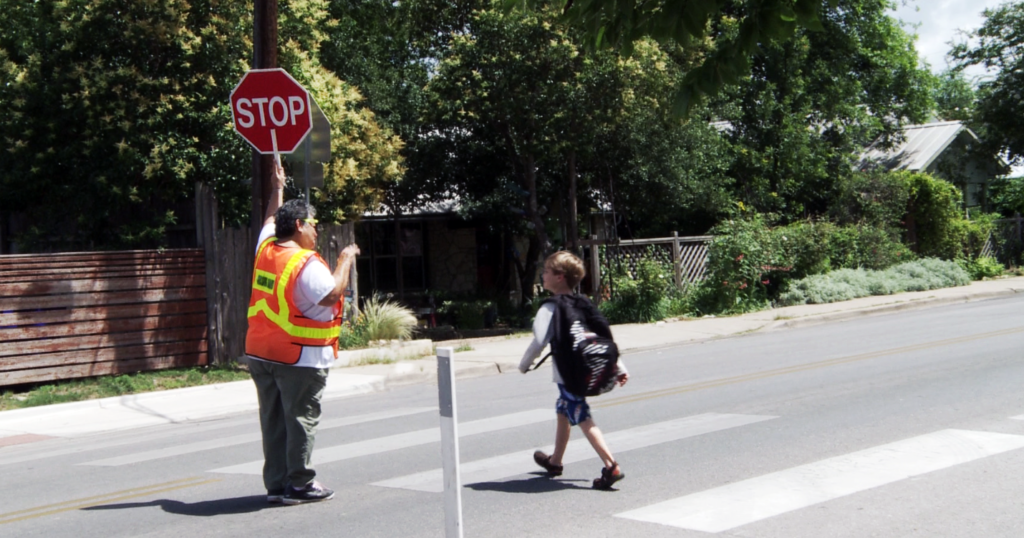 AgriLife pedestrian safety pic of child in crosswalk with crossing guard.