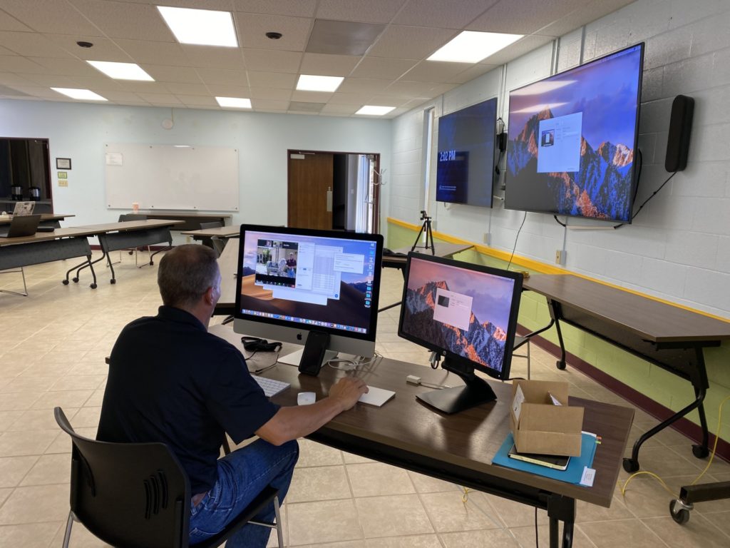 Man sitting in front of multiple monitors at an AgriLife conference room during Sheep and Goat Expo