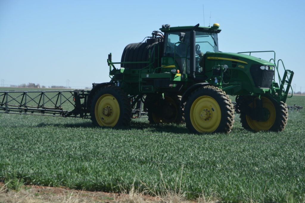 Close up of ground rig spraying pesticide on a wheat field