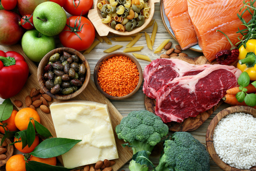 A wide variety of healthy foods on a table illustrate some of the items that Cooking Well with Diabetes class will cover. Among the items, all fresh, include steak, cheese, broccoli, tomatoes, salmon rice, olives, almonds, oranges and peppers.