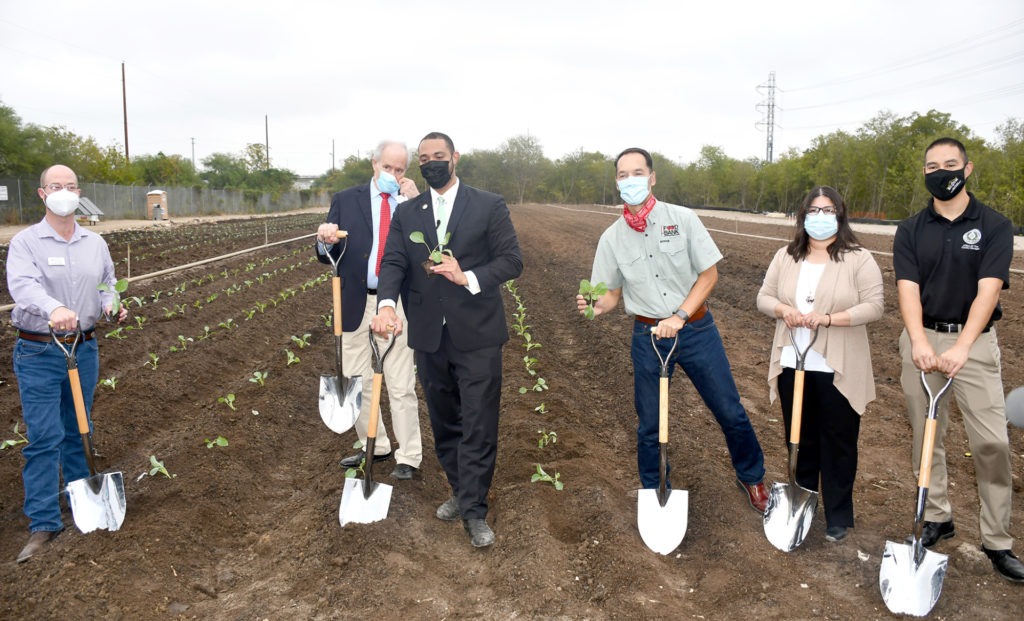 Group of people masked with shovels standing in the Greenies field for a groundbreaking