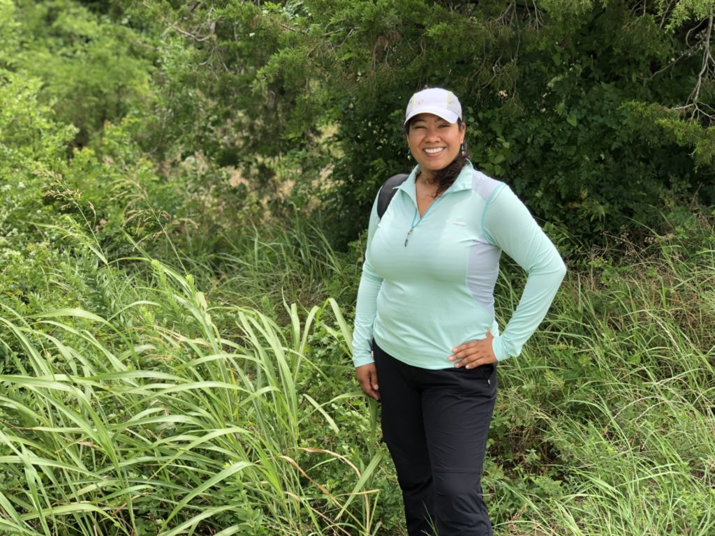Aggie Jocelyn Holt standing in a field where she studies sugarcane aphids.