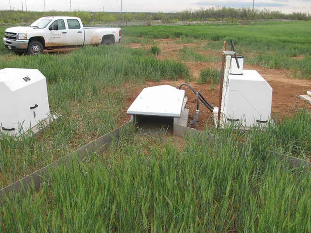 White equipment on the edge of a field that will measure water runoff quality after the use of dairy manure 