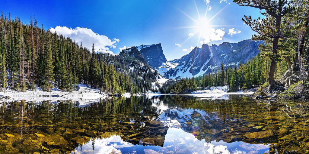 beautiful picture of the Rocky Mountain Hallett Peak reflected in a lake and surrounded by trees
