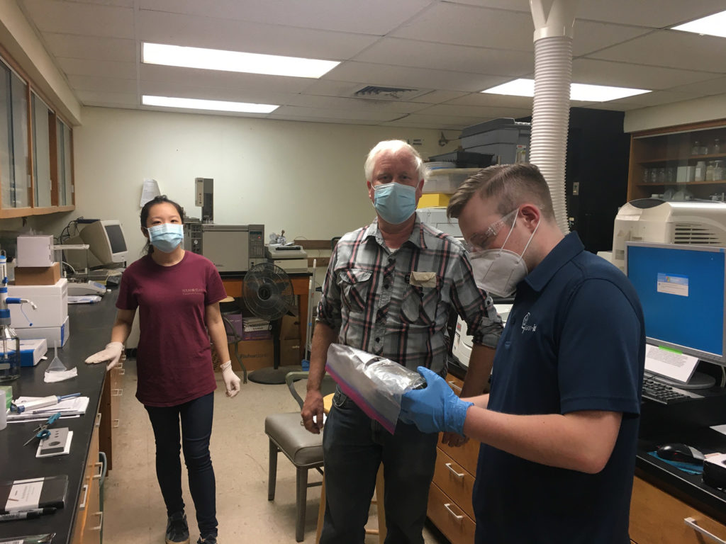 Three people in a lab setting prepare to run a hemp test through new equipment