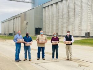 Western Rice Belt Conference committee - five people standing outside in front of elevators holding packages of rice.