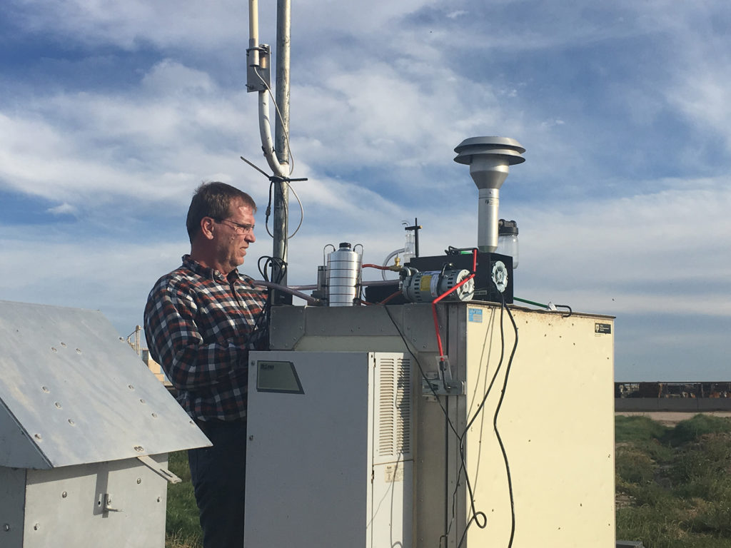 Brent Auvermann stands at the controls of air quality equipment.