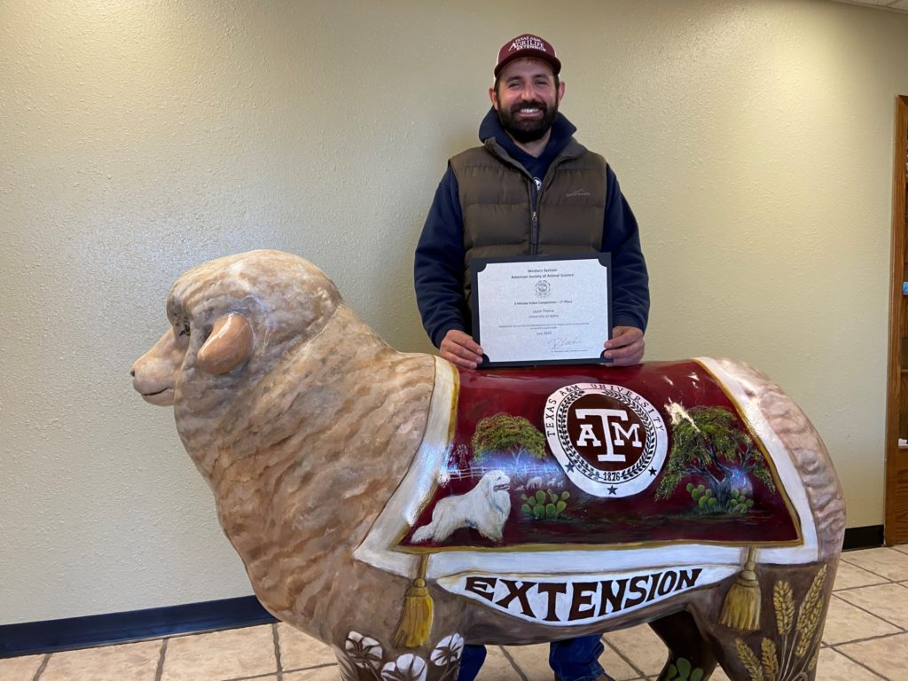 Texas A&M AgriLife's Jake Thorne holding his award from ASAS in front of a sheep statue