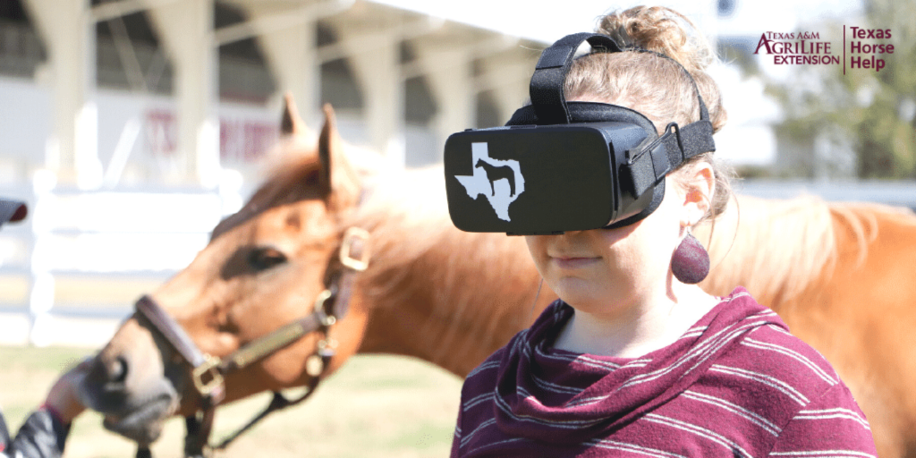 Girl with virtual reality goggles on standing beside a horse.