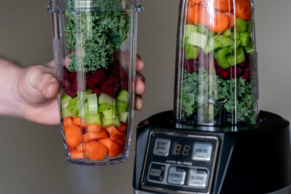 juicing machines filled with carrots, celery, beets and kale