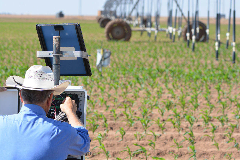 a man, Thomas Marek, works at the control box to adjust the center-pivot automation and control system