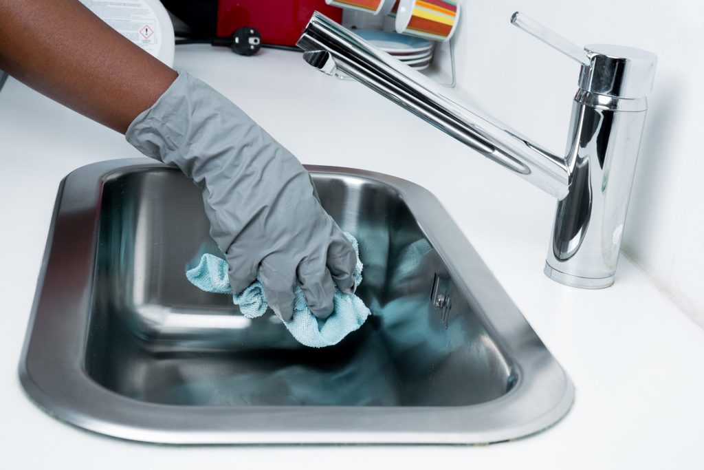 Gloved hand cleaning a kitchen sink