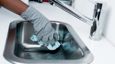 Gloved hand cleaning a kitchen sink