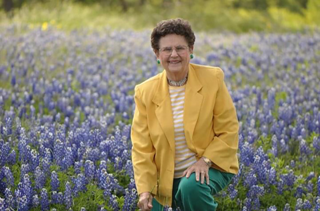 Lady in yellow jacket, June Helwig, in a field of bluebonnets