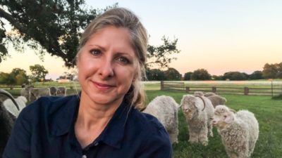 Dawn Brown, MD, stands in a field in front of her Angora goats.r