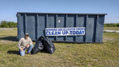 Participant in 2021 Geronimo and Alligator Creeks Cleanup Event in front of dumpster