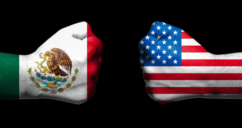 Two fists, one each draped with the Mexico and U.S. flags