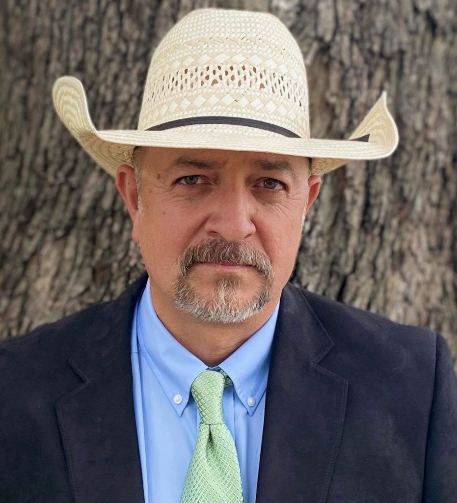 Headshot of Fred Sanchez wearing a blazer, tie and cowboy hat