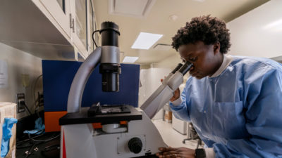 Female student looking into microscope.