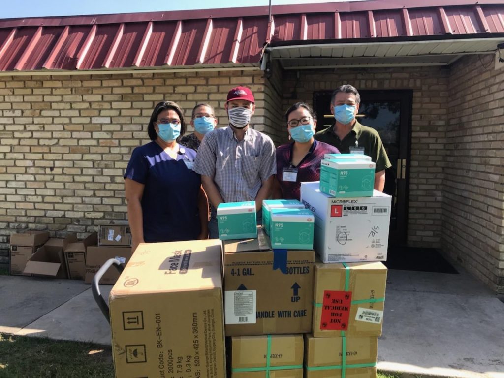Five people, all masked, stand behind a stack of boxes when a PPE delivery was made to long-tern care facility during the COVID-19 pandemic/disaster