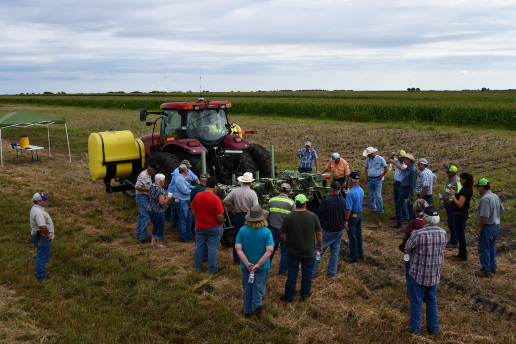 tractor in field surrounded by people attending a field day