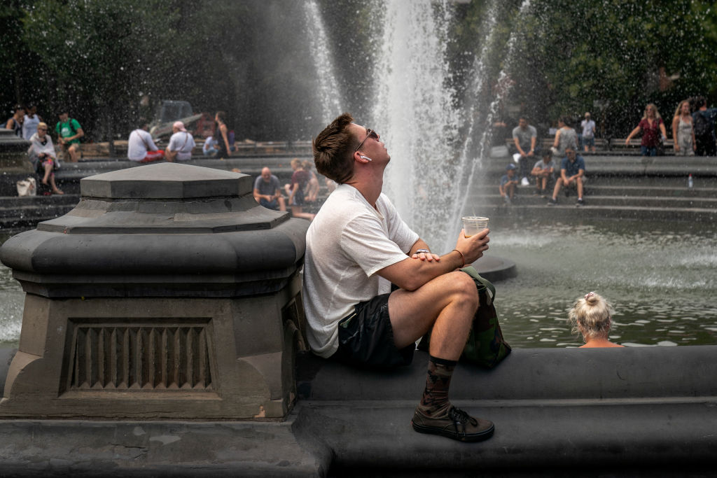 Man with cup of water sitting near fountain on a sunny day