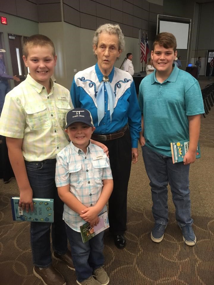 Dr. Temple Grandin stands with three children at the Texas A&M AgriLife Extension 2021 Sandhills Beef Cattle Conference. They are s with three 