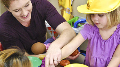 Early childhood educator and child with hard hat