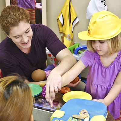 Child educator with child wearing toy hard hat