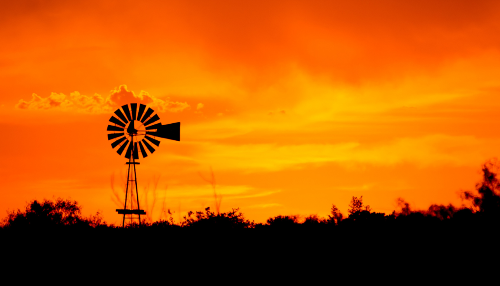 A sunset picture with a windmill on the horizon