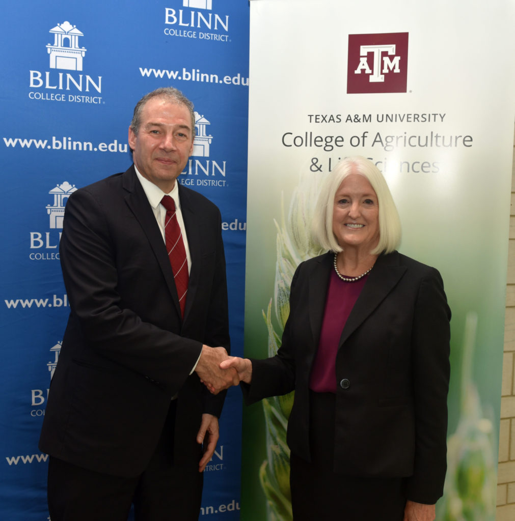 Patrick J. Stover and Mary Hensley shake hands at the articulation agreement signing
