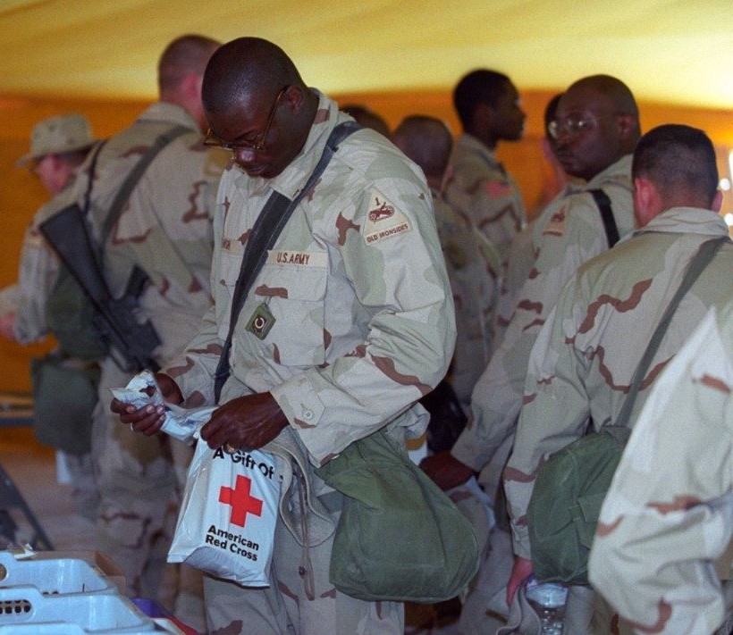 Soldiers stand reading Red Cross literature.