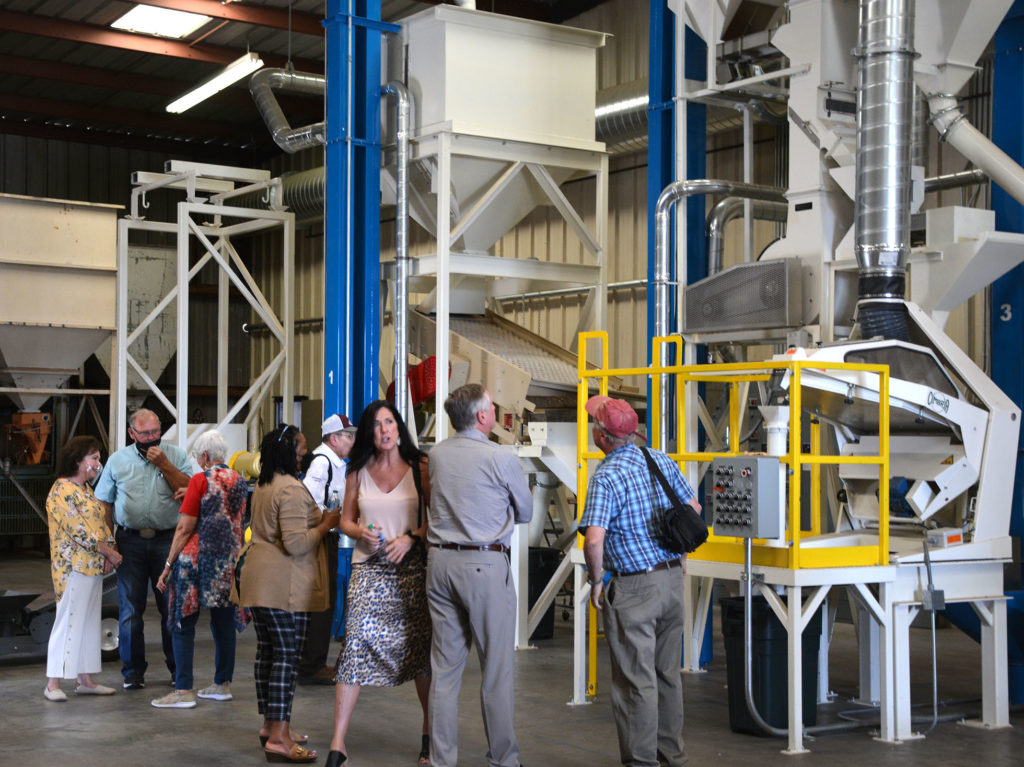 three large legs of the peanut sheller with people in front of the white, blue and yellow machinery