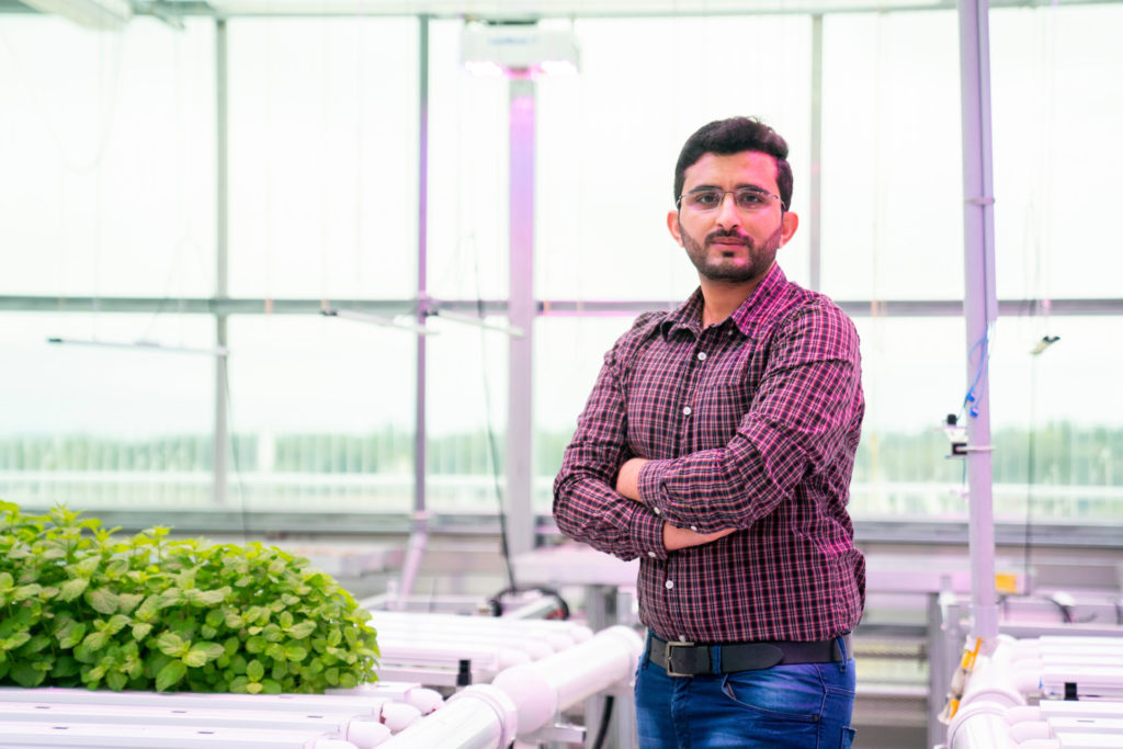 Zahid stands next to urban growing area greenhouse in Dallas