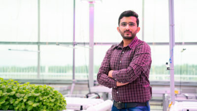 Zahid stands next to urban growing area greenhouse in Dallas