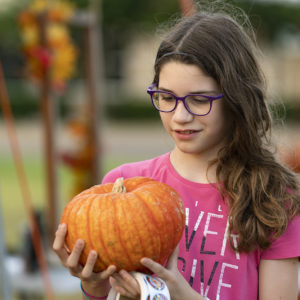 Young girl holds an orange pumpkin