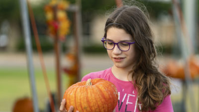 Young girl holds an orange pumpkin